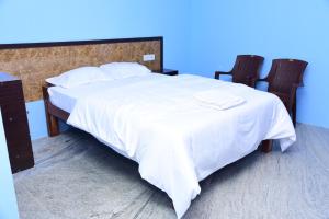 a bedroom with a large white bed with two chairs at Thangam Residency in Kāraikkudi