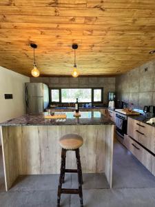 a kitchen with a wooden ceiling and a bar with a stool at Chalet San Rafael (Villa 25 de Mayo) in San Rafael