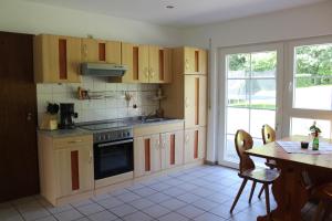 cocina con armarios de madera, mesa y ventana en Zum Hasenbahnhof, en Kirchhundem