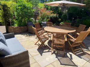 a wooden table with chairs and an umbrella on a patio at Sunny Dale in Niton