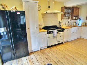 a kitchen with a black refrigerator and white cabinets at Sunny Dale in Niton