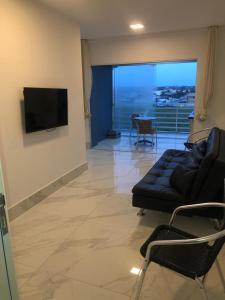 a living room with a couch and a flat screen tv at Apartamento no Edifício Florida Terrace in Matinhos