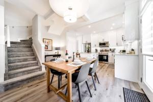 a kitchen and dining room with a wooden table and chairs at Modern Nordic Escape, 3BR Near WEM & DT, AirCon & Fireplace, Wifi, Sleeps 6! in Edmonton