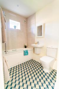 a bathroom with a toilet and a tub and a sink at Chestnut Cottage at Gravel Farm in Stretham