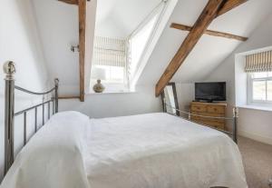 ein weißes Schlafzimmer mit einem Bett und einem Fernseher in der Unterkunft Upper Deck, Port Isaac Bay Holidays in Port Isaac