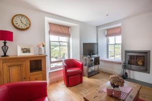 ein Wohnzimmer mit einem roten Stuhl und einer Uhr an der Wand in der Unterkunft Upper Deck, Port Isaac Bay Holidays in Port Isaac