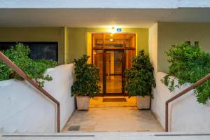 a hallway leading to a door with two plants at COZY STUDIO in RETHYMNO TOWN in Rethymno Town