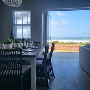 a dining room table and chairs with a view of the ocean at Villa Laks in Kiddʼs Beach