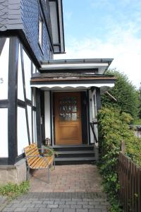 a house with a wooden door and a chair on a patio at Ferienwohnung an der Hundem in Kirchhundem