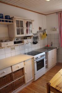 uma cozinha com armários brancos e um forno com placa de fogão em Ferienwohnung an der Hundem em Kirchhundem