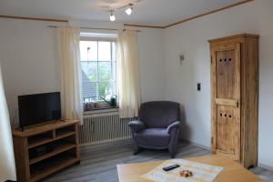 a living room with a chair and a television at Ferienwohnung an der Hundem in Kirchhundem