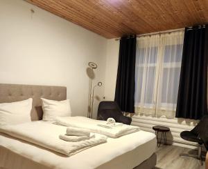 a bedroom with a bed and a chair and a window at Niederdreisbacher Hof in Niederdreisbach
