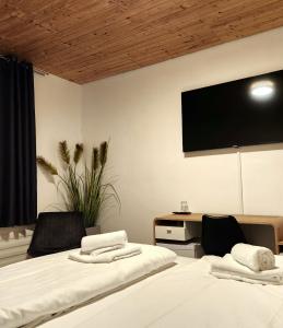a bedroom with two beds and a tv on the wall at Niederdreisbacher Hof in Niederdreisbach