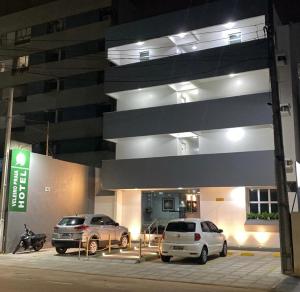 two cars parked in front of a building at night at Veleiro Praia Hotel in Maceió