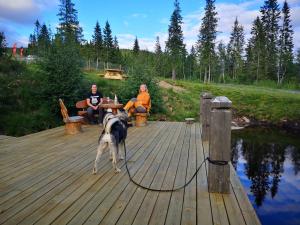 zwei Personen und ein Hund stehen auf einer Holzterrasse in der Unterkunft Blåfjell hundesenter fjellhotell in Mosjøen