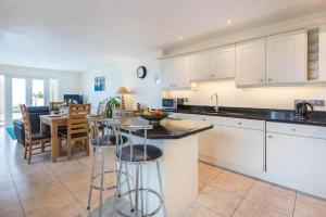 a kitchen with white cabinets and a table with bar stools at Sea Gem, Port Isaac Bay Holidays in Port Isaac