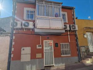 um edifício vermelho com uma varanda e uma porta em APARTAMENTO MADRID Norte em San Sebastián de los Reyes