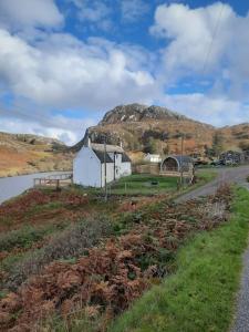 a building on the side of a road next to a mountain at Handa pod in scottish highlands. in Scourie