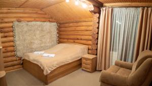 una camera da letto in una baita di tronchi con un letto e una sedia di Mini Hotel Laplandiya a Bukovel