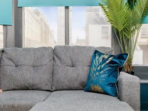 ein blaues Kissen auf einer grauen Couch mit einem Fenster in der Unterkunft Your Central Stay 5 bedroom flat in Brighton & Hove