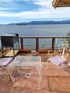 a deck with two chairs and a table and a grill at Melipal Schuss ARG41 in San Carlos de Bariloche