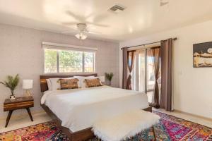 a bedroom with a large white bed and a window at Tortoise Oasis - Hot tub, Shuffleboard, & More! in Yucca Valley