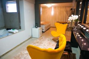 a living room with yellow chairs and a table at Hotel Pedra Negra Gov. Valadares in Governador Valadares