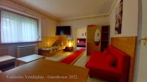 sala de estar con sofá rojo y chimenea en Vadászles Vendégház, en Bükkszentmárton