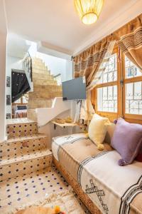 2 Betten in einem Zimmer mit einem TV und einer Treppe in der Unterkunft Dar BAB HAHA Petite Maison à la Marocaine in Tangier