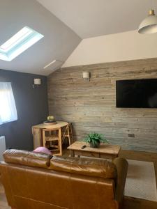 sala de estar con sofá de cuero marrón y TV de pantalla plana en The Old Stable en Bugbrooke