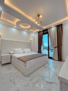 - une chambre blanche avec un grand lit et des portes en verre dans l'établissement sharm luxury apartment in sharm hills, à Charm el-Cheikh