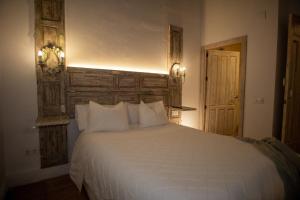 a bedroom with a white bed with a wooden headboard at Apartamentos Sharis in Jerez de la Frontera