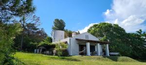 ein weißes Haus auf einem Hügel mit Bäumen in der Unterkunft La Calma Casa de Campo - Villa Parque Siquiman in Villa Parque Siquiman