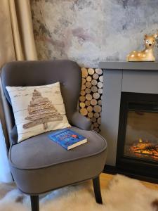 une chaise avec un livre à côté d'une cheminée dans l'établissement Pinewood ANG Apartment, Semiramida Borovets Hills, à Borovets