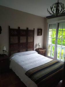 a bedroom with a large bed and two windows at Finca La Sierra in Castrillón