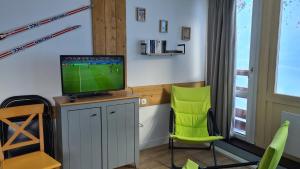 a living room with a tv and green chairs at Appartements Bozeman in La Mongie