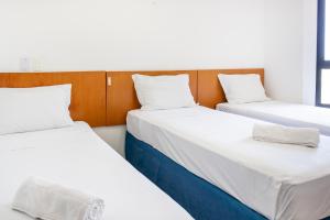 three beds in a room with white sheets and pillows at Praia a Vista Salvador Hotel in Salvador