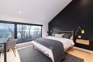 - une chambre avec un grand lit et une grande fenêtre dans l'établissement Le Lo - Fleuve - Forêt - Spa - 10 min du Massif, à Petite-Rivière-Saint-François