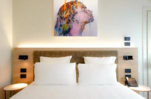 Una cama con almohadas blancas y una pintura encima. en Bergamo INN 21, en Bérgamo