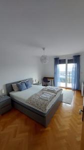 1 dormitorio con 1 cama grande y suelo de madera en MED MAN Apartmani, en Slavonski Brod