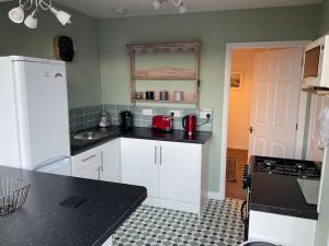 cocina con armarios blancos y encimera negra en Comfy and welcoming 2 bedroom Annex., en Padstow