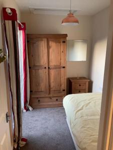 a bedroom with a bed and a wooden cabinet at Comfy and welcoming 2 bedroom Annex. in Padstow +2 photos