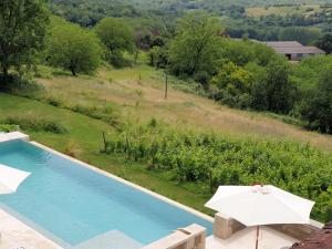 an outdoor swimming pool with an umbrella at Le Haut Repaire in Coubjours