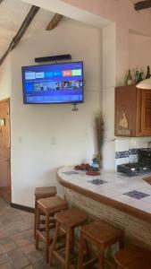 a kitchen with a bar with stools and a tv on the wall at Villa Vacacionales Los Cayos Con Playa Privada in Boca de Aroa