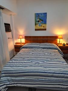 1 dormitorio con 1 cama de rayas y 2 lámparas en BA Downtown Callao en Buenos Aires