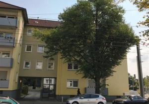 un edificio amarillo con un árbol delante de él en Living-Life, Klinik & Messe vor Ort, Wlan, Netflix, en Essen