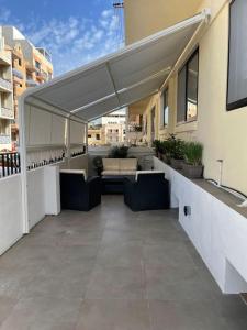 un patio con sillas y toldo en un edificio en Luxurious sunlit maisonette with large terrace! en Marsaskala