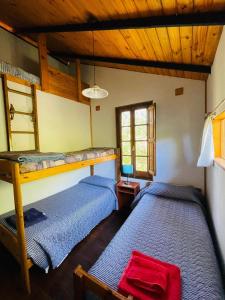 two beds in a room with wooden ceilings at Cabaña El Cristo in La Cumbre