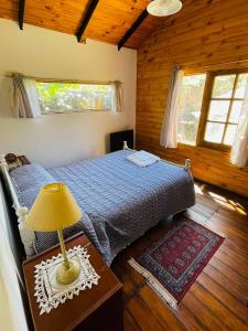 a bedroom with a bed and a lamp on a table at Cabaña El Cristo in La Cumbre