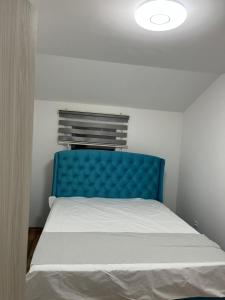 a bed with a blue headboard in a room at Cezar Apartments in Podgorica